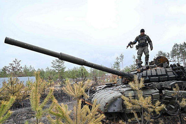 Ukrainian soldier mounts a destroyed Russian tank in Ukraine