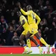 Mateta (middle) wheels away in celebration with a teammate, as Arsenal's Odergaard kneels, dejected