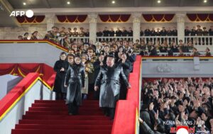 North Korean leader in a matching uniform with her daughter during a military parade.
