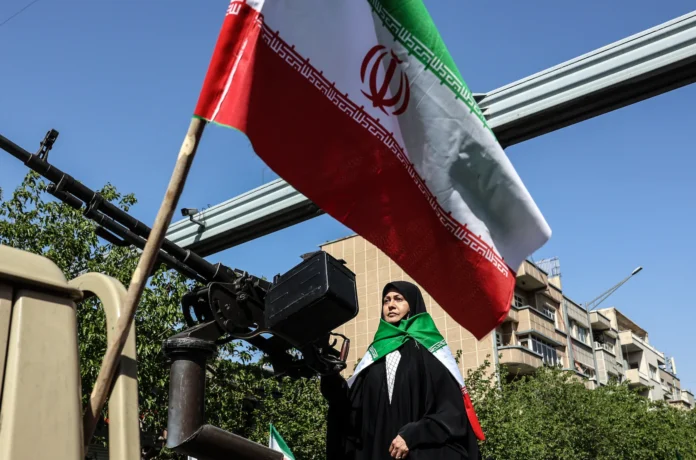 a woman close to iranian flag in tehran.